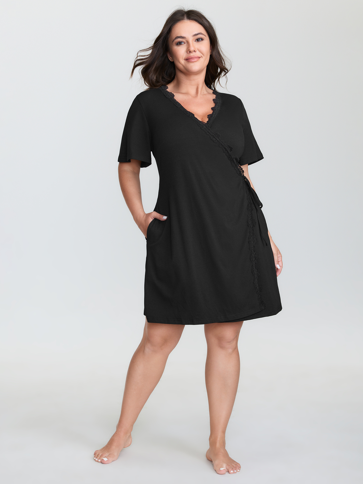 Side view of BloomChic Women's Plus Size Lace Trim Side-Tie Pockets Nightgown Black Short sleeve Mini V-Neck 30/6X
