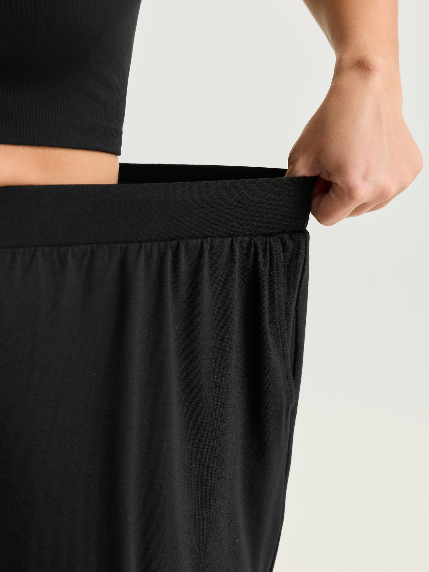 Side view of BloomChic Women's Plus Size Supersoft Stretchy Cuffed Cropped Lounge Bottoms Black Capri 14-16/1X