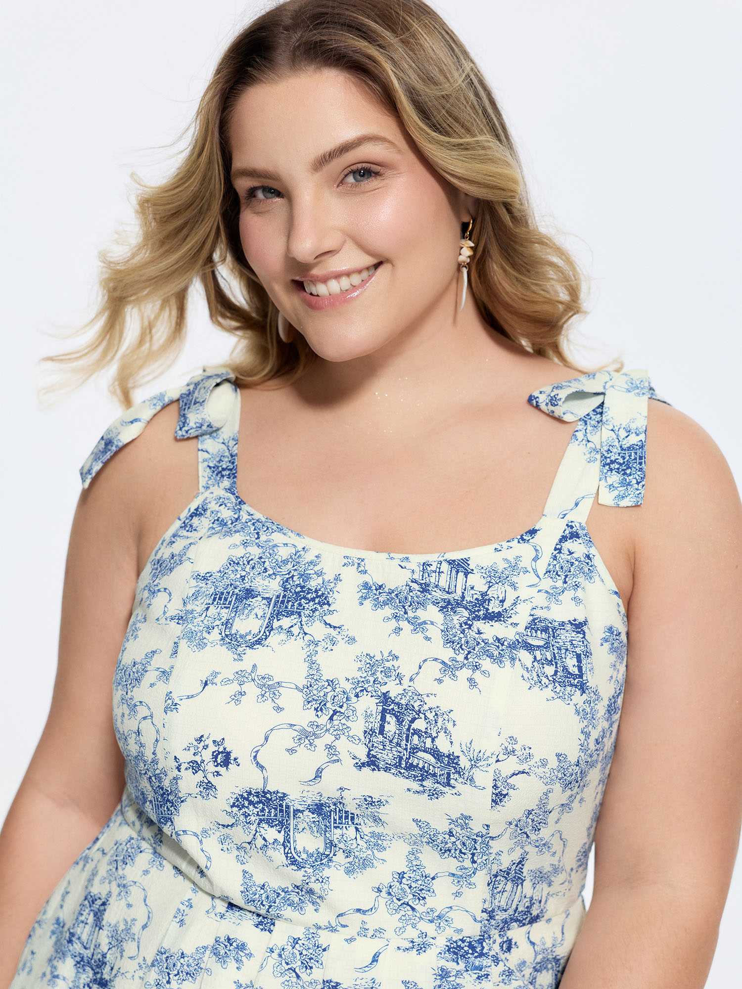 Side view of BloomChic Women's Plus Size Garden Print Adjustable Shoulder-Tie Romper Indigo Vacation 22-24/3X