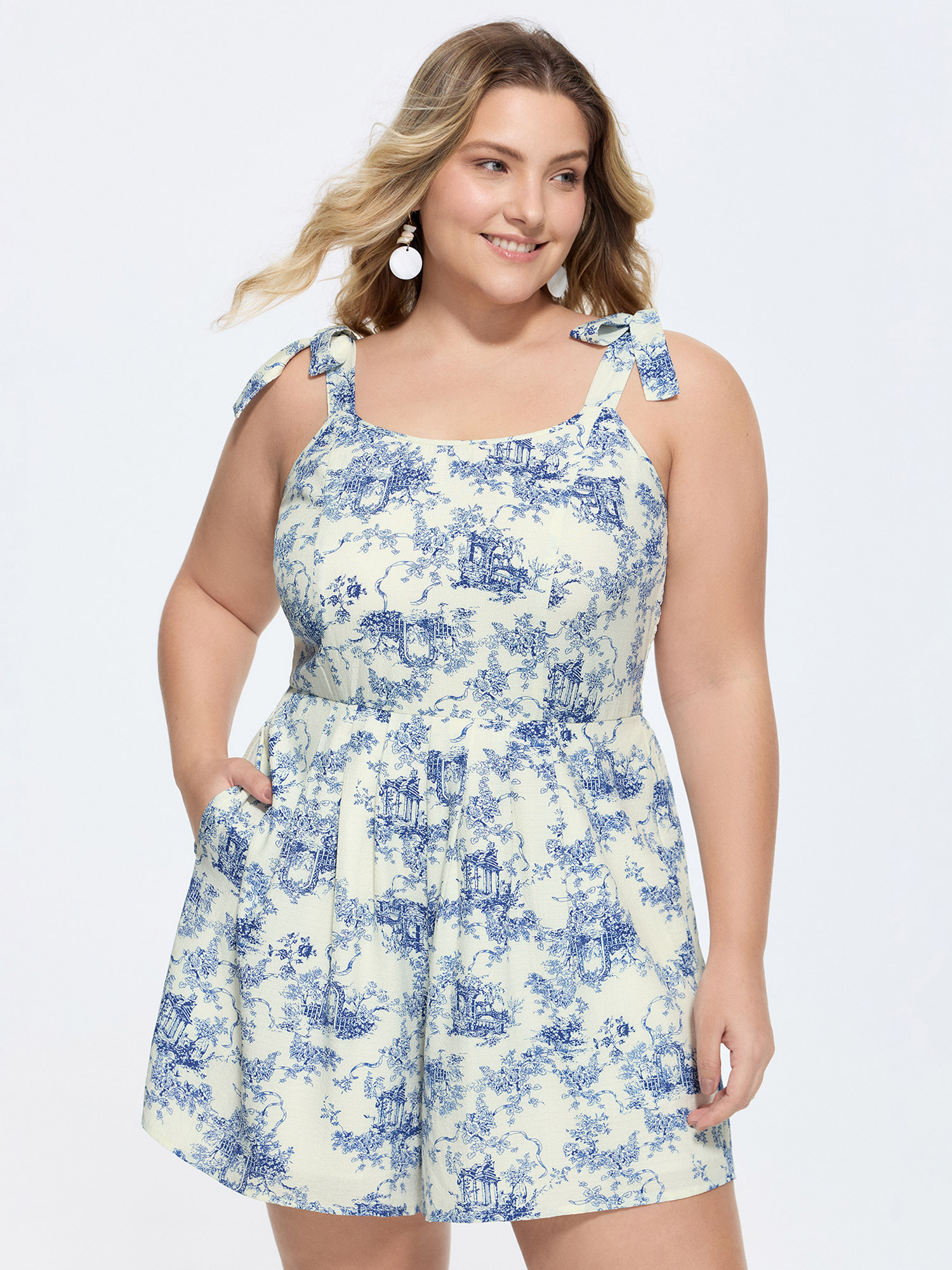 Side view of BloomChic Women's Plus Size Garden Print Adjustable Shoulder-Tie Romper Indigo Vacation 22-24/3X