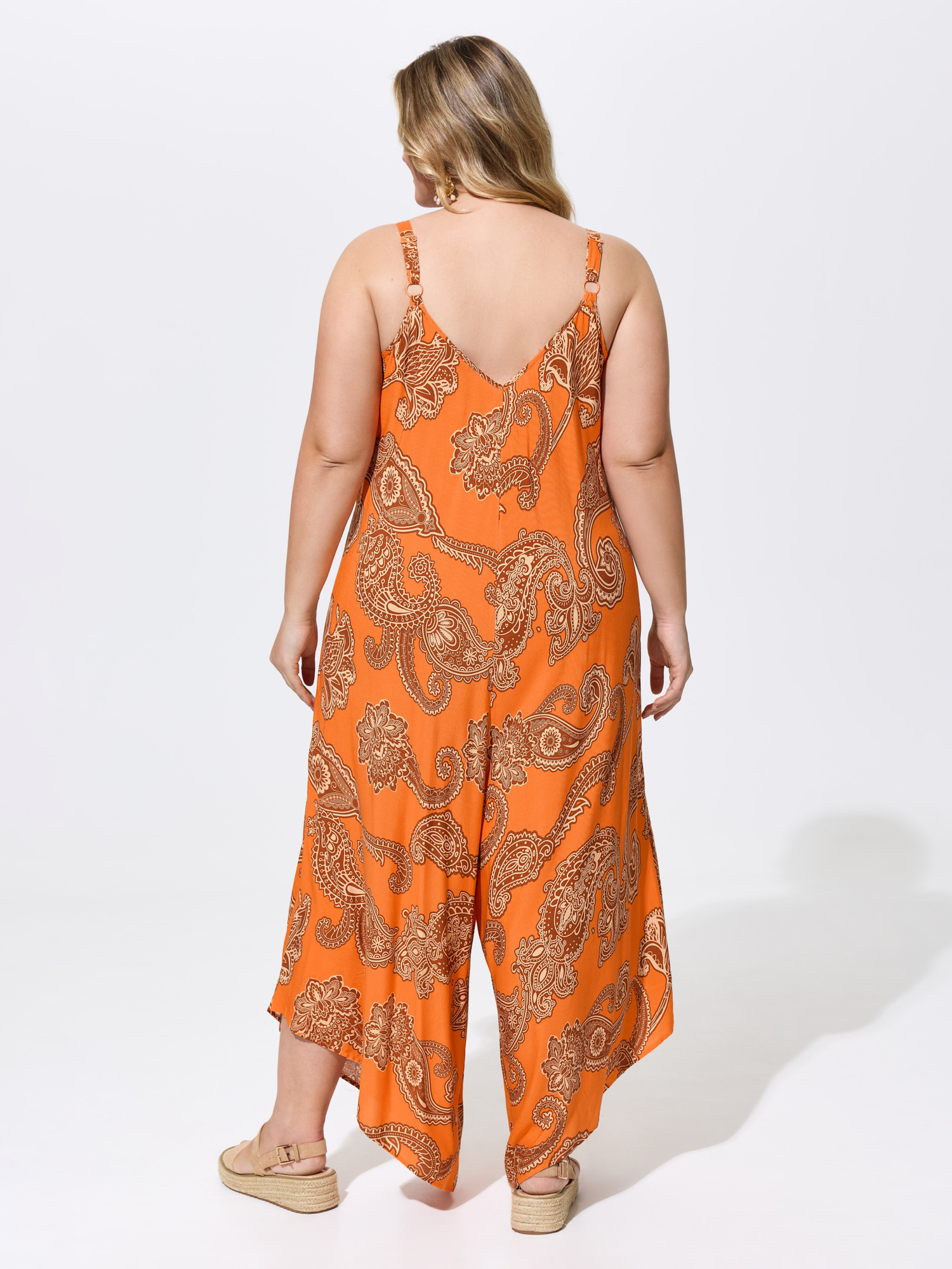 Side view of BloomChic Women's Plus Size Boho Print Asymmetrical Hem Jumpsuit Brightorange Vacation 12/L
