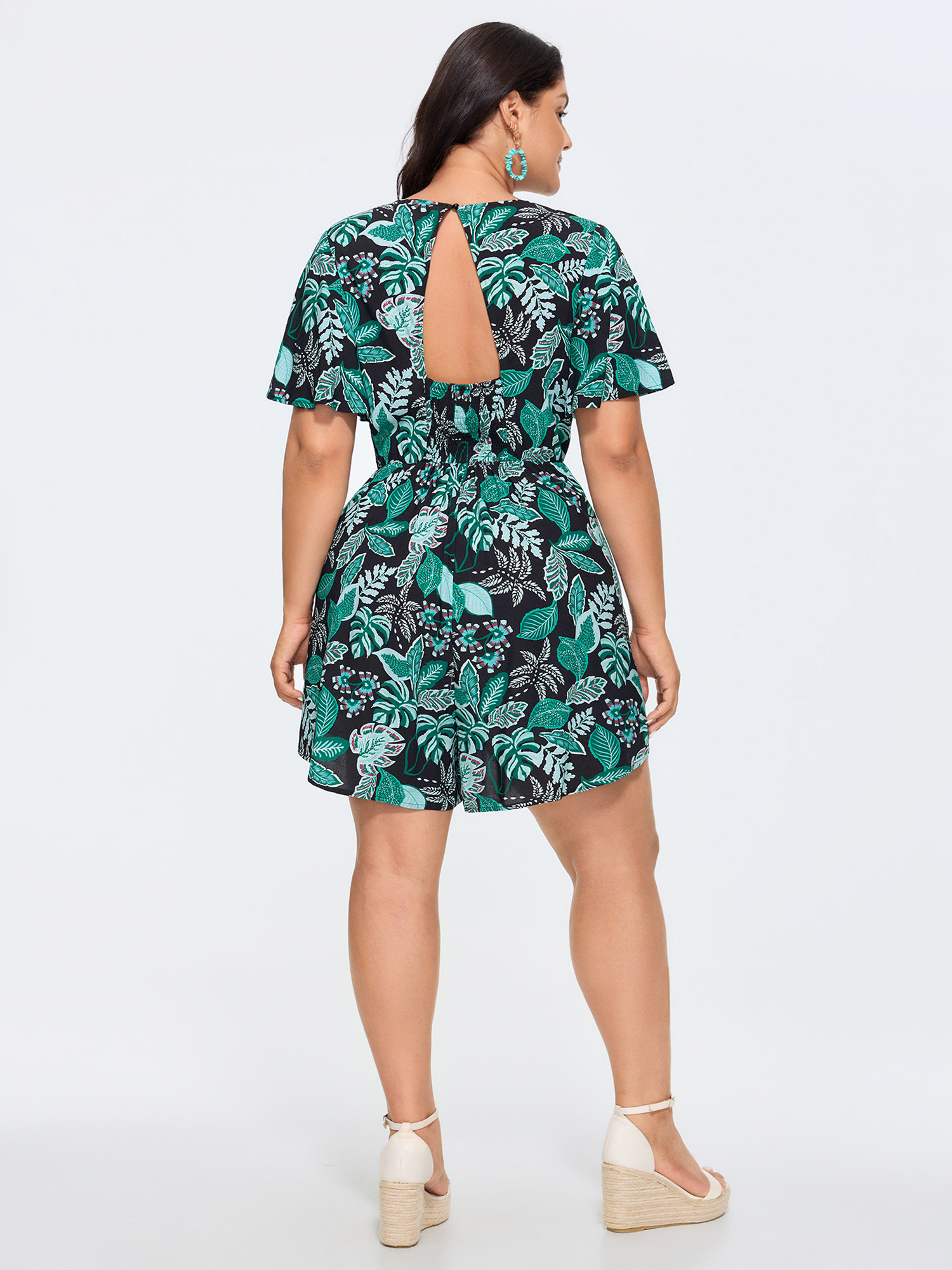 Side view of BloomChic Women's Plus Size Tropical Print Cut-Out Back Romper Black Vacation 14-16/1X